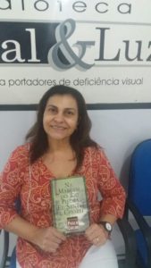 Foto de Maria Inês segurando o livro ao qual foi ledora