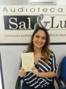 Ledora Maristela de Nigro sorrindo sentada com o livro na mão